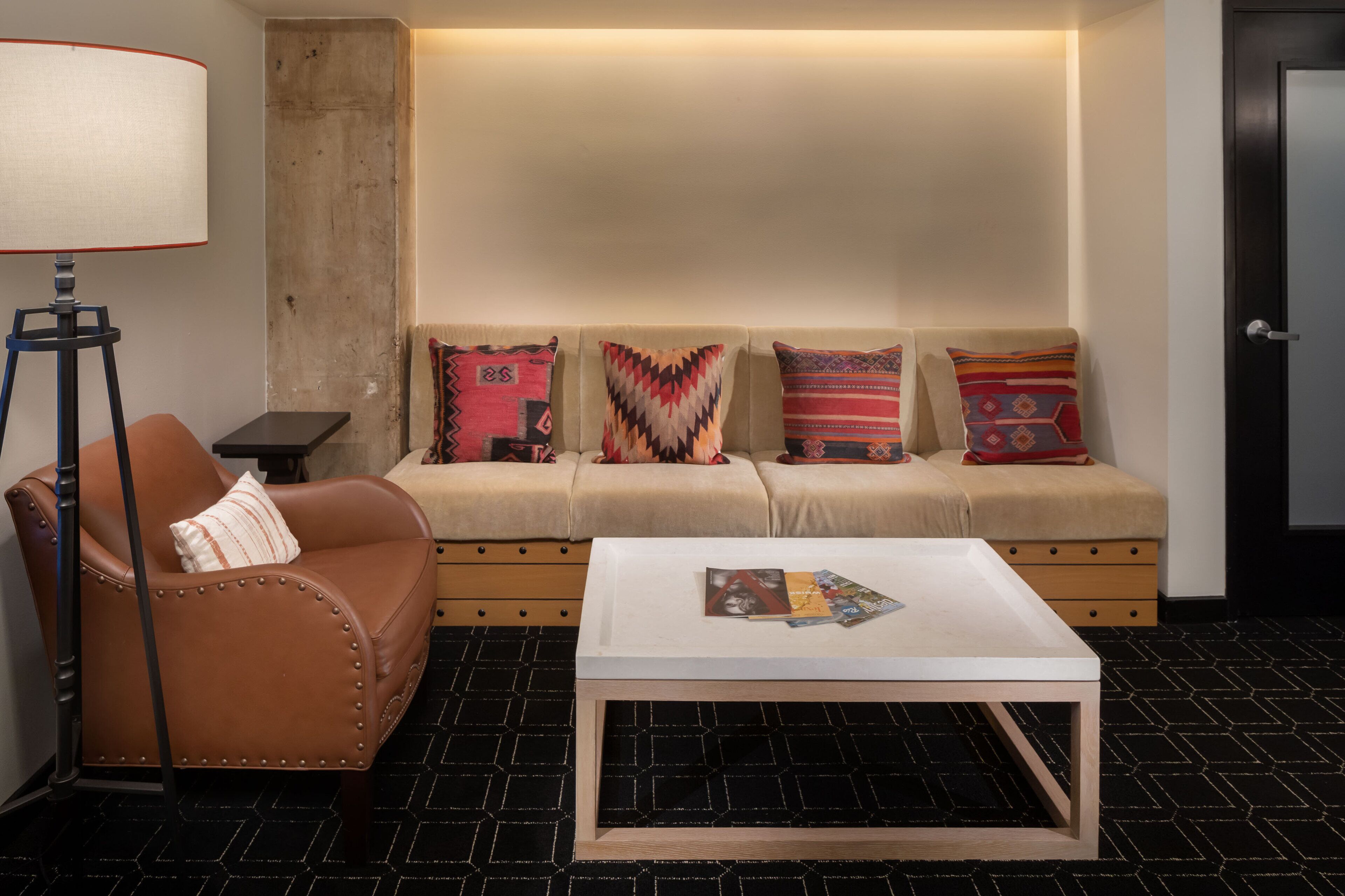 A living room with a sofa, a coffee table, a lamp, and patterned cushions.