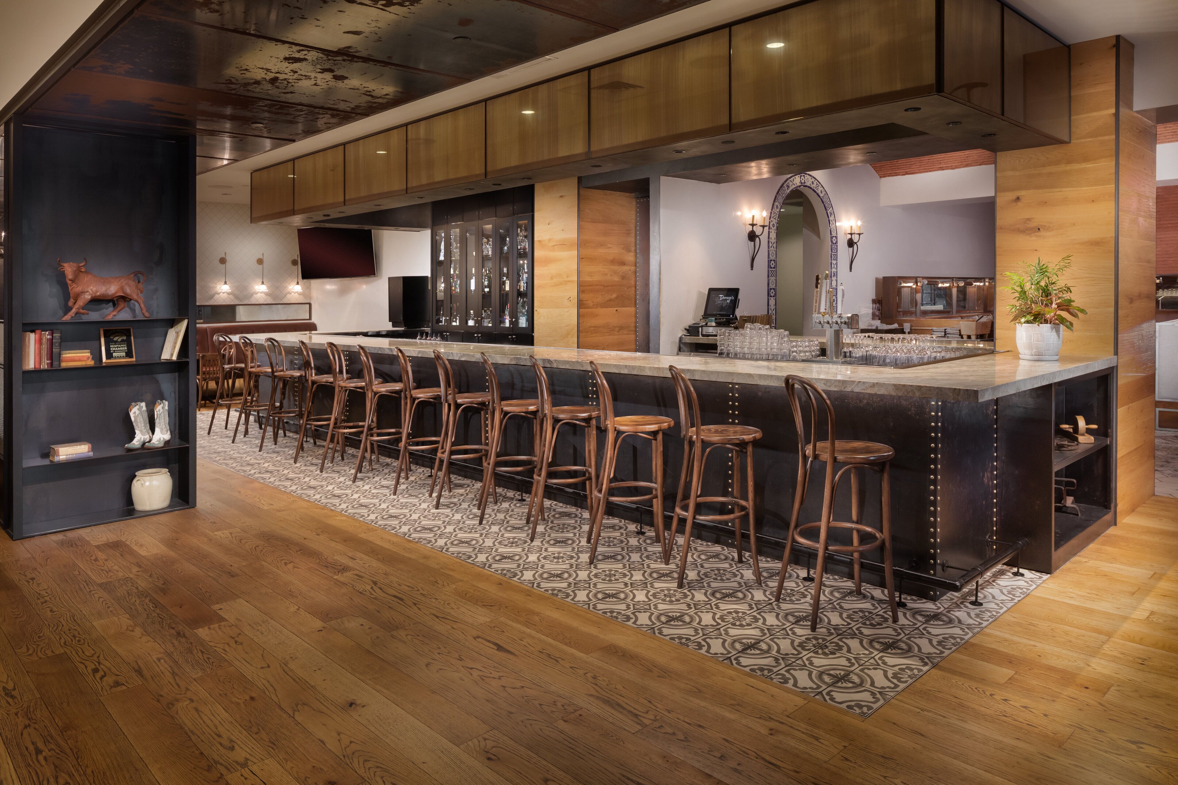 Une cuisine moderne dotée d’un long comptoir-bar, de meubles en bois et d’un tapis à motifs.