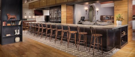 A modern kitchen with a long bar area, wooden cabinets, and a patterned rug.