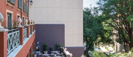 A hotel courtyard with outdoor seating, a water feature, and a tall building in the background.