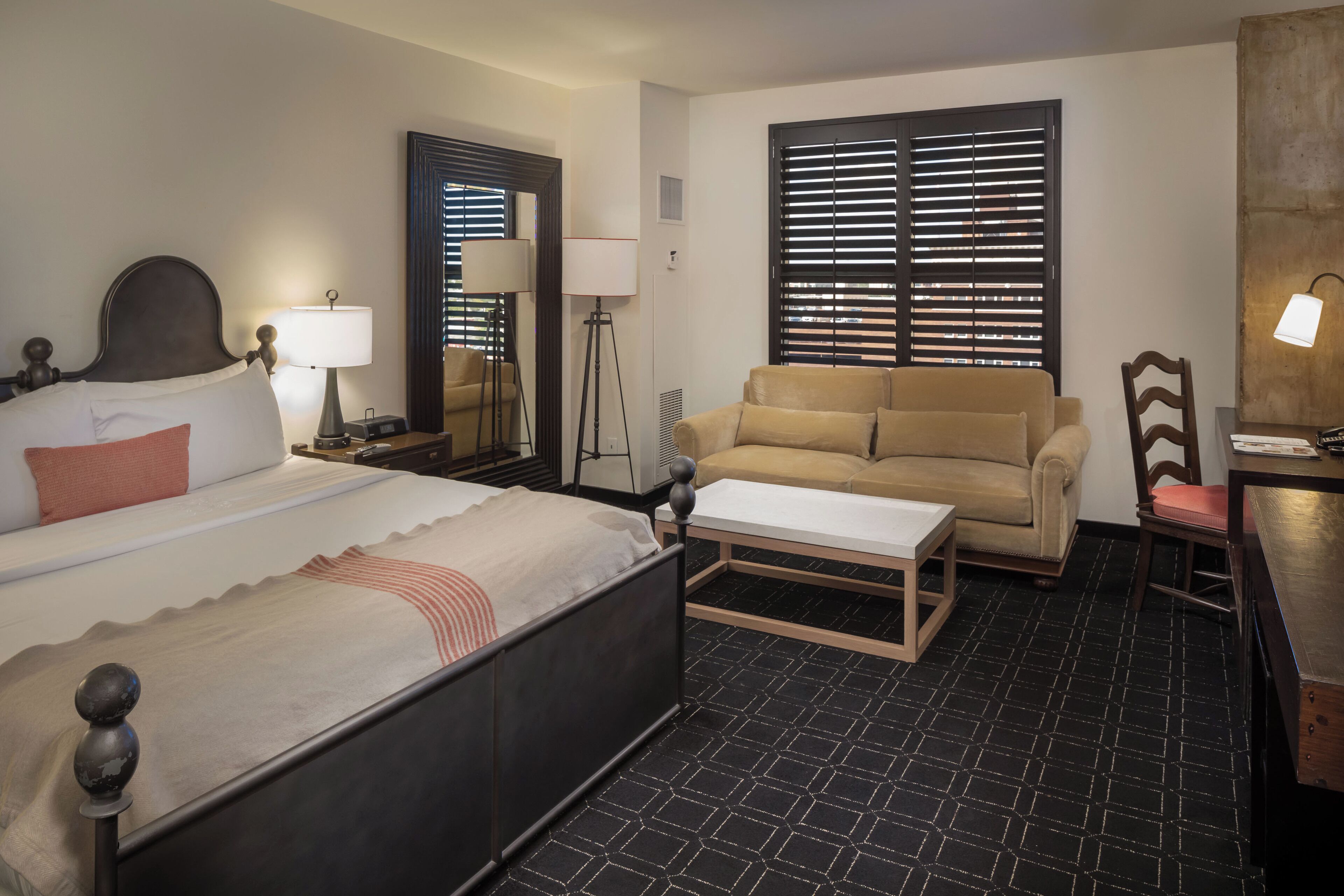 Een hotelkamer met een bed, een bank, een salontafel en een stoel.