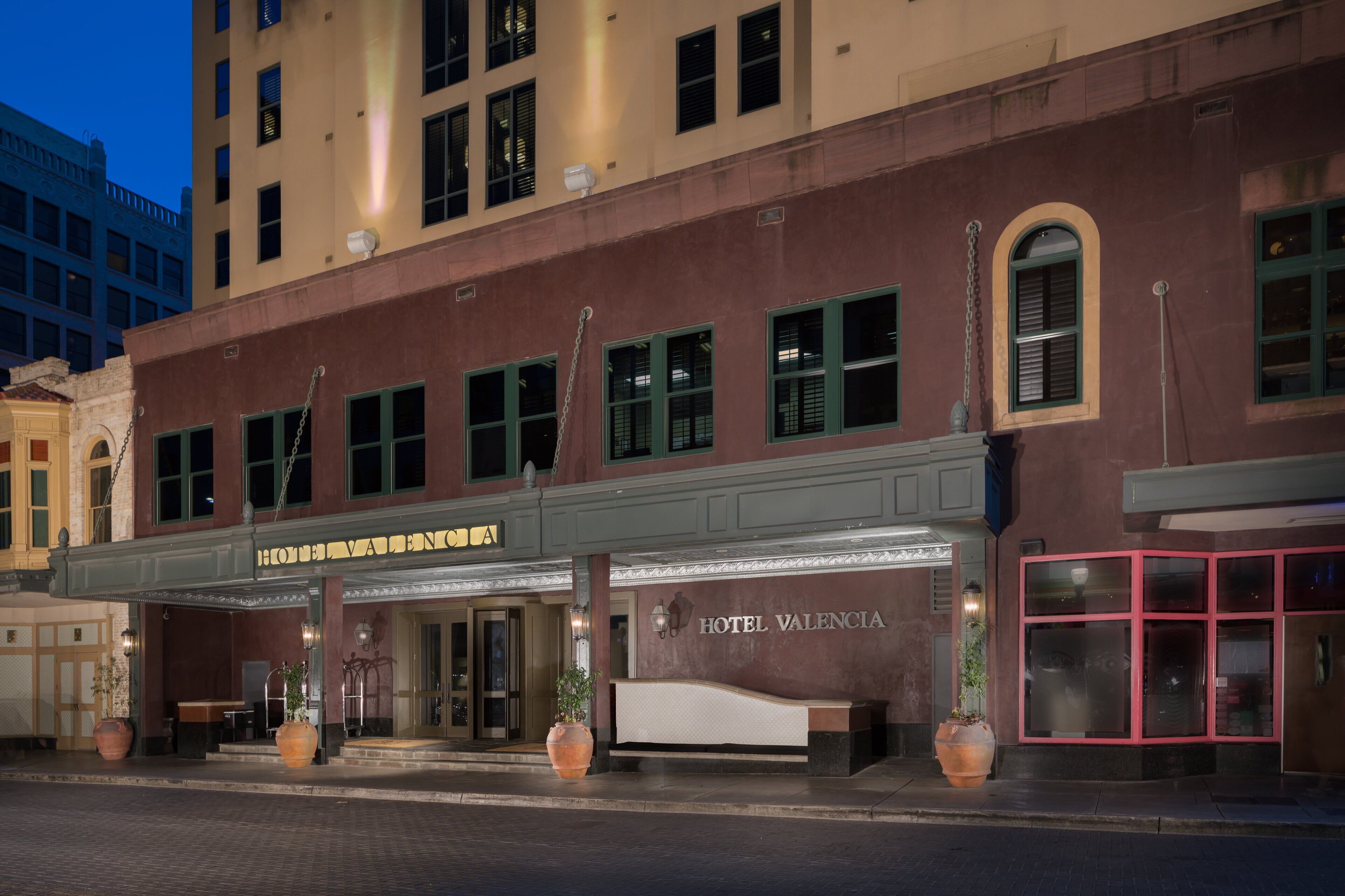 A hotel facade with a marquee sign, large windows, and a reception desk.