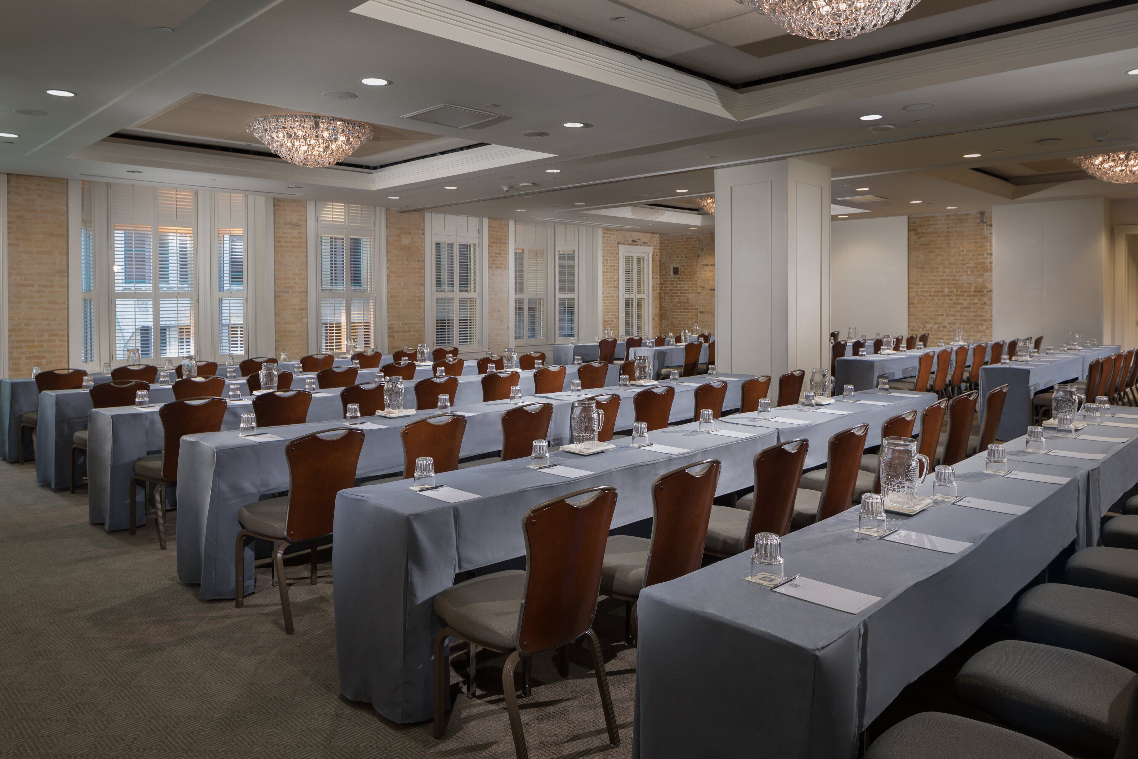 Une salle de conférence avec de longues tables, des chaises et des lustres.