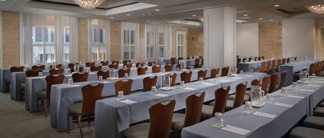 Une salle de conférence avec de longues tables, des chaises et des lustres.
