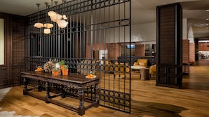 A wooden dining table with a decorative metal partition, potted plants, and a fruit bowl.