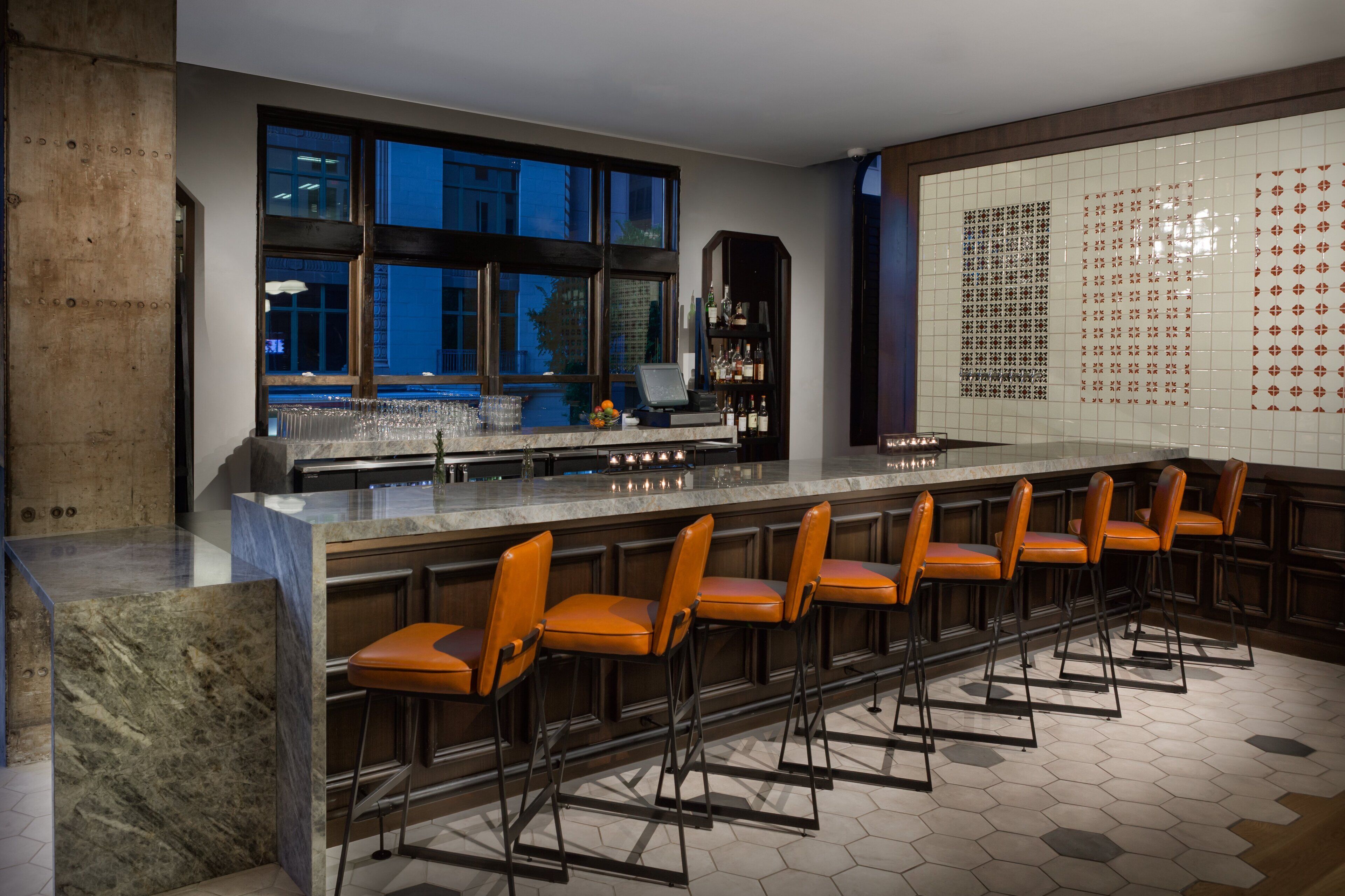 A modern kitchen with a bar area, large windows, and a tiled backsplash.