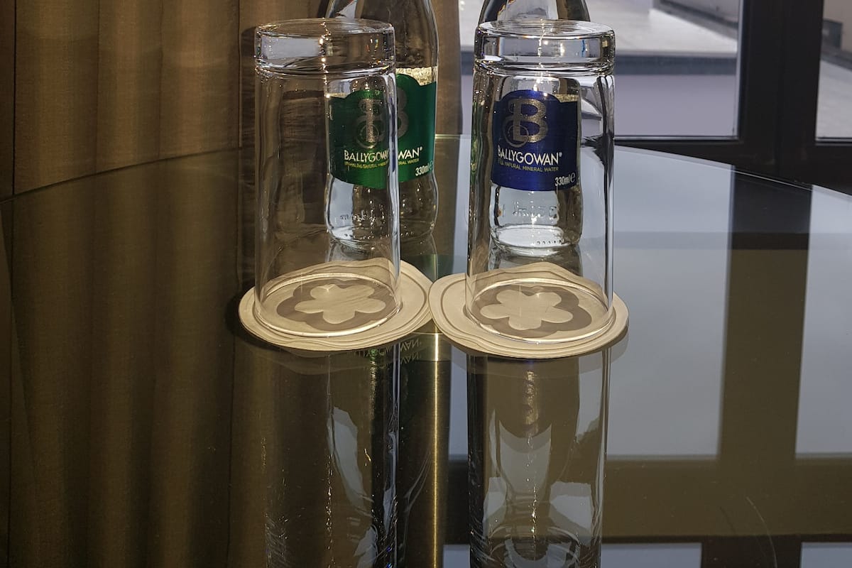 Two bottles and two glasses on a reflective surface with a view of a building and a clock tower in the background.