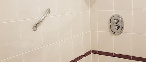 A bathroom with a bathtub, a showerhead, and a toilet.