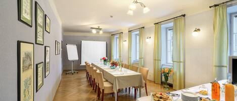 A conference room with a long table, chairs, a whiteboard, and a buffet table with various food items.