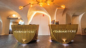 Een receptie met twee balies, voorzien van de naam 'Bellevue Hotel', een moderne kroonluchter en een vloer met een honingraatpatroon.