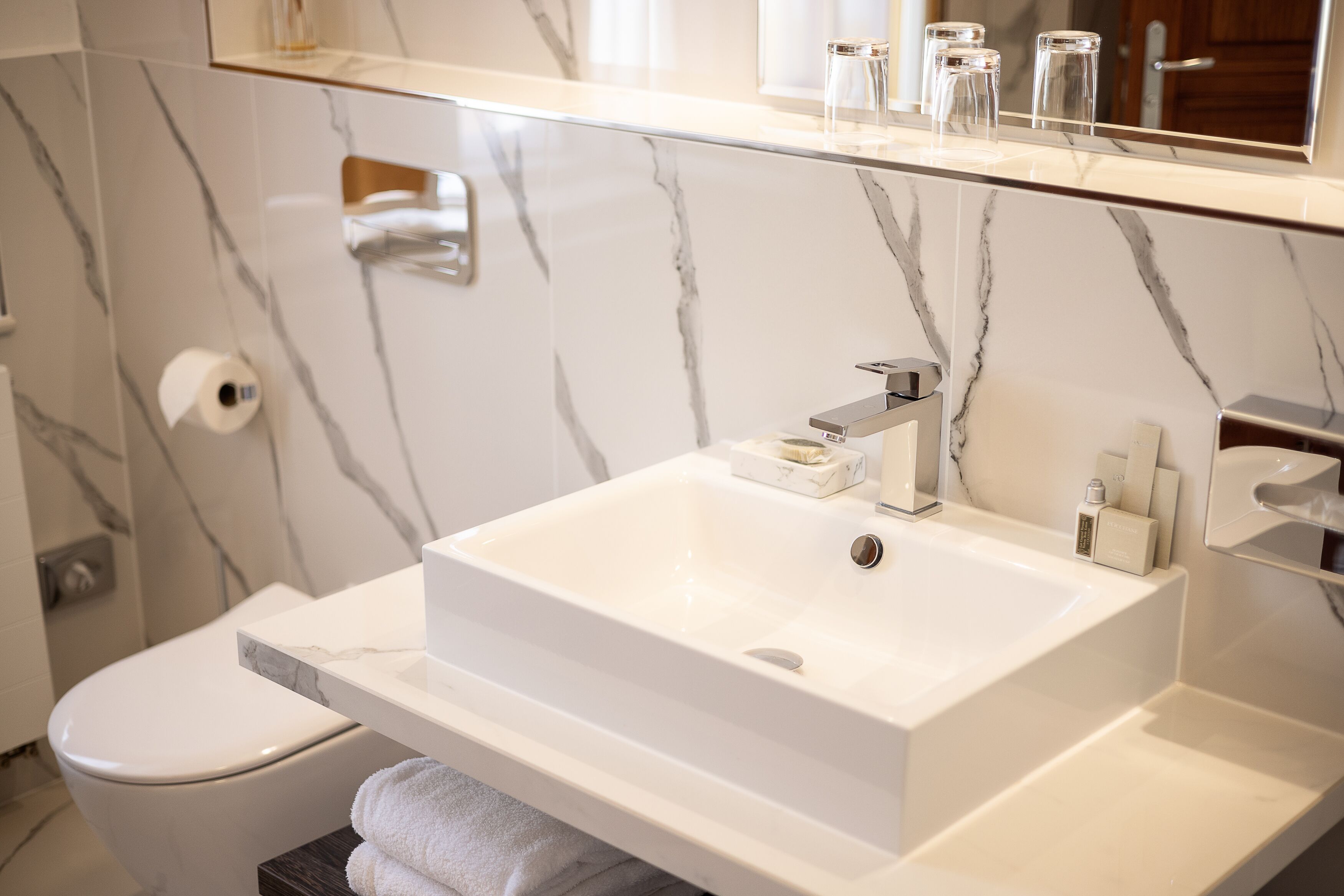 Ein Badezimmer mit einem weißen Marmorwaschbecken, einer Toilette und einem Spiegel über dem Waschbecken.