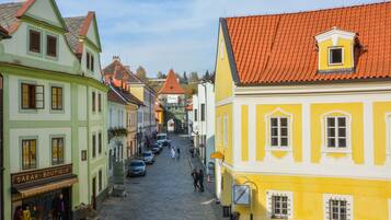 A cobblestone street lined with colorful buildings, including a boutique and a yellow building with a red roof.