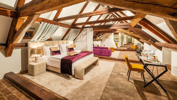 Een slaapkamer met een groot bed, een nachtkastje, een stoel en een bureau met een stoel.