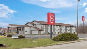 A Red Roof Inn with a modern building, a parking lot, and a clear sky.
