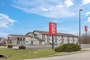 A Red Roof Inn with a modern building, a parking lot, and a clear sky.