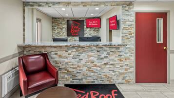 A reception area with a stone wall, a red door, a red leather chair, and a sign indicating free Wi-Fi in all rooms.