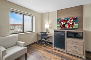 A hotel room with a large window, a desk with a chair, a television, a microwave, and a mini-fridge. - Red Roof Inn Ames (Ames)