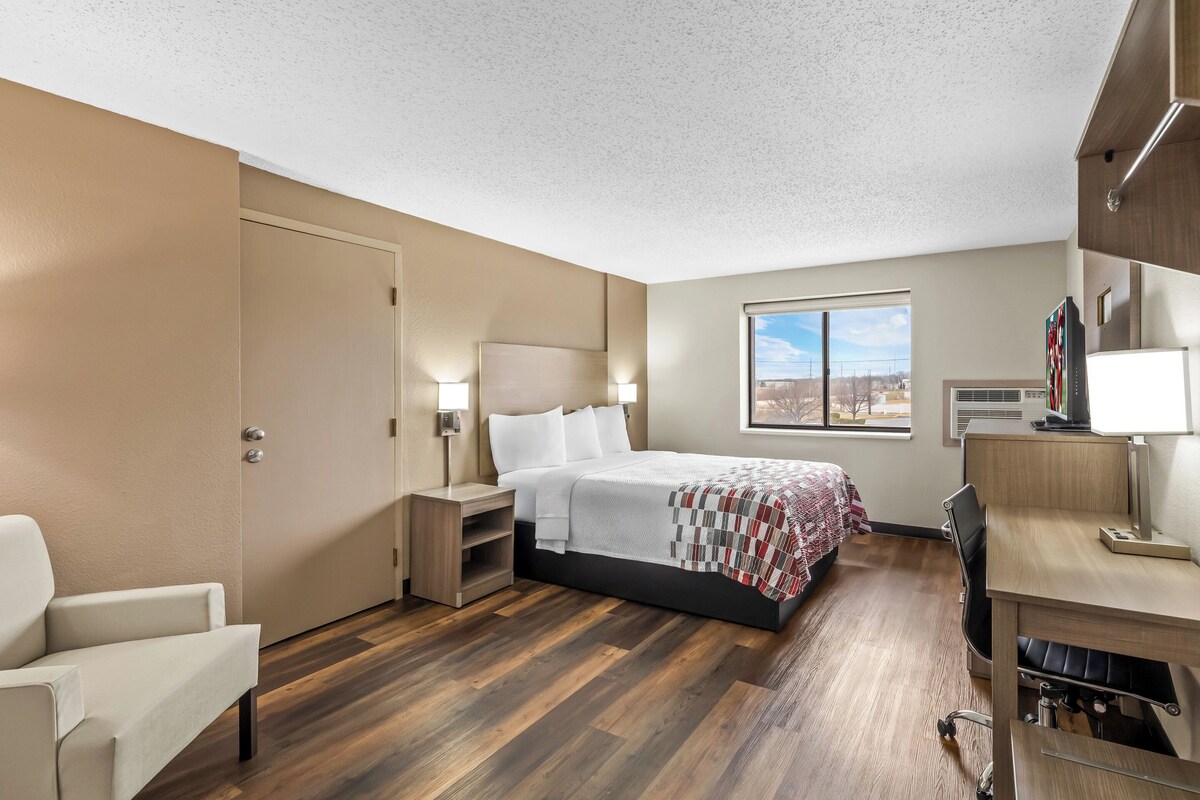 Una habitación de hotel con cama, escritorio, silla y vistas a la ciudad.