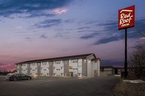 A Red Roof Inn building with a parking lot and a car.