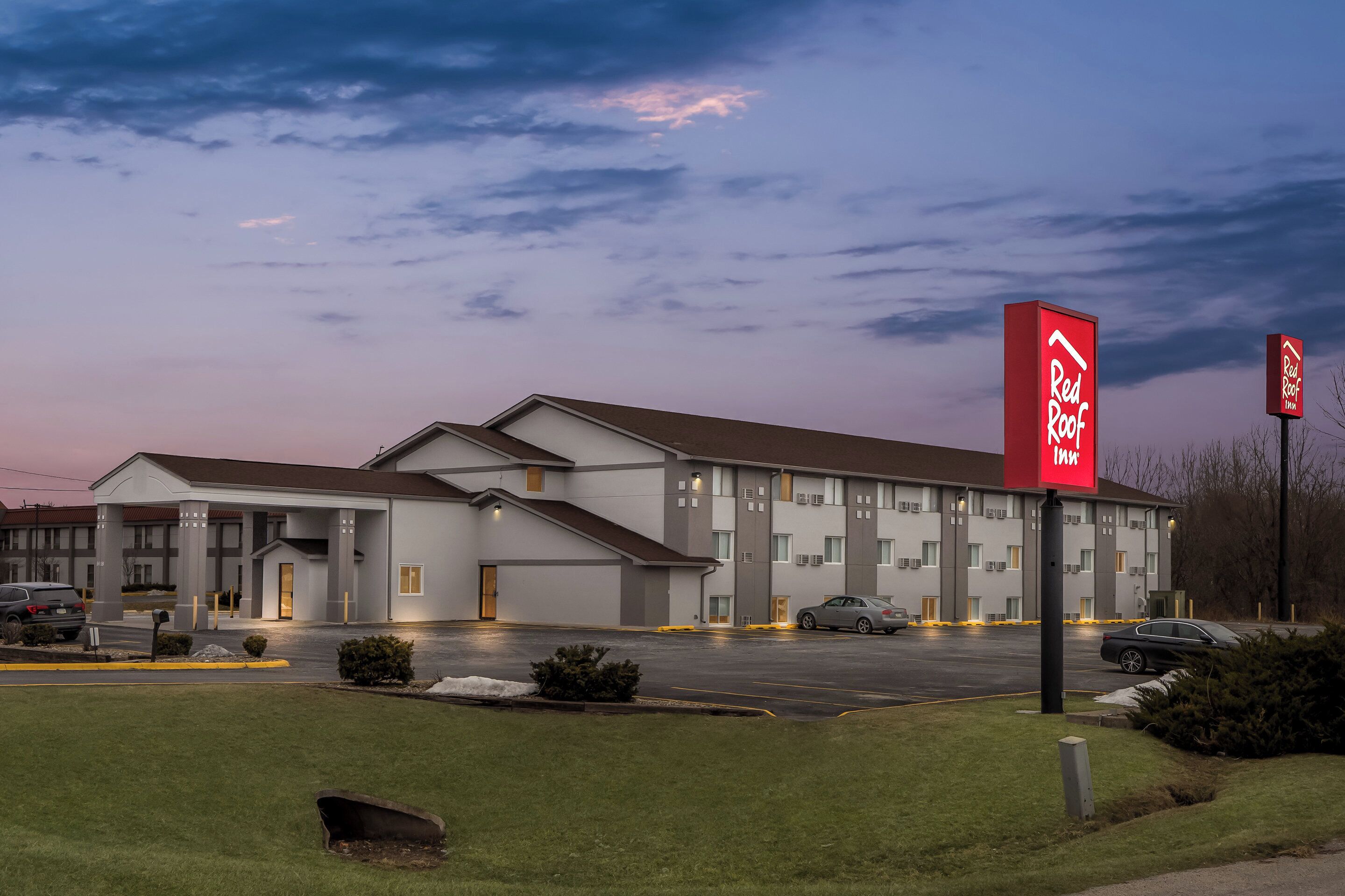 A Red Roof Inn with a two-story building, a parking lot, and a well-maintained lawn.