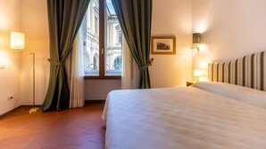 A hotel room with a large bed, a window with curtains, a wall-mounted picture, and a bedside lamp. - La Casa del Ghiberti B&B (Florence)