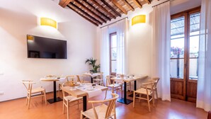 A dining area with hexagonal floor tiles, wooden tables and chairs, and a flat-screen TV mounted on the wall. - La Casa del Ghiberti B&B (Florence)