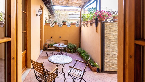 A courtyard with a table and chairs, potted plants, and a pergola. - La Casa del Ghiberti B&B (Florence)