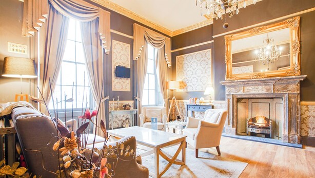 A spacious living room with a fireplace, comfortable seating, and a large mirror.