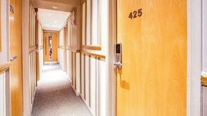 A hotel hallway with doors numbered 424 and 425, a carpeted floor, and a sign indicating the direction to the elevator.