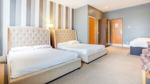 A hotel room with two beds, a wooden wardrobe, a desk, and a chair.