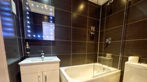 A modern bathroom with a vanity, bathtub, and toilet.