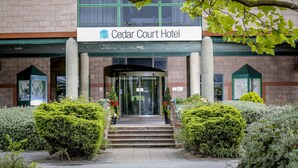 The Cedar Court Hotel entrance with a brick facade, glass doors, and a green awning. - Cedar Court Wakefield (Wakefield)