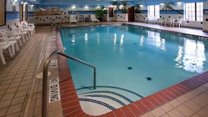 An indoor swimming pool with a tiled floor, a pool ladder, and white lounge chairs around the pool area. - Quality Inn & Suites, Near University (Waco)