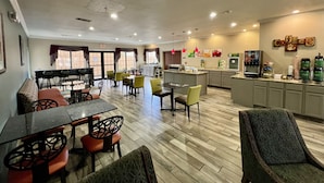 A hotel lobby with a dining area, a kitchen, and a coffee station. - Quality Inn & Suites, Near University (Waco)