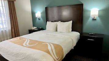 A hotel room with a large bed, two bedside tables, a nightstand with a phone, and wall-mounted lights.