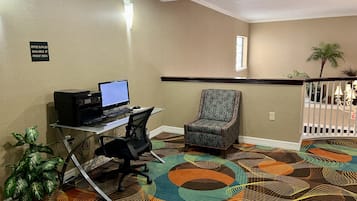 Une chambre d’hôtel équipée d’un bureau, d’un ordinateur, d’une chaise et d’une moquette à motifs.