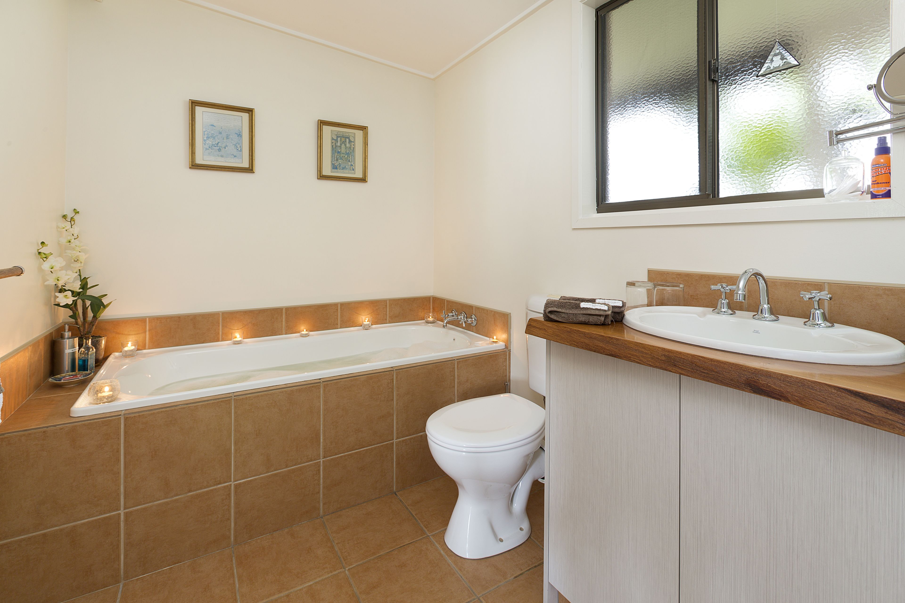 A bathroom with a bathtub, toilet, and sink. There are two framed pictures on the wall.