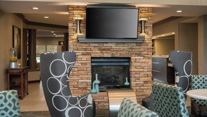 A modern lounge area with a stone fireplace, comfortable seating, and a flat-screen TV mounted above the fireplace. - Residence Inn by Marriott Cypress Los Alamitos (Los Alamitos)