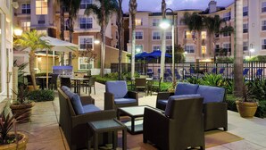 An outdoor patio area with wicker furniture, a grill, and umbrellas. - Residence Inn by Marriott Cypress Los Alamitos (Los Alamitos)