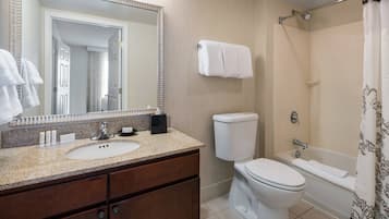 A bathroom with a sink, mirror, toilet, and bathtub.