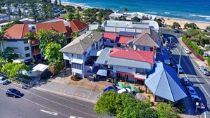 Un hotel frente al mar con varias construcciones, un estacionamiento y vistas a la playa y al océano.