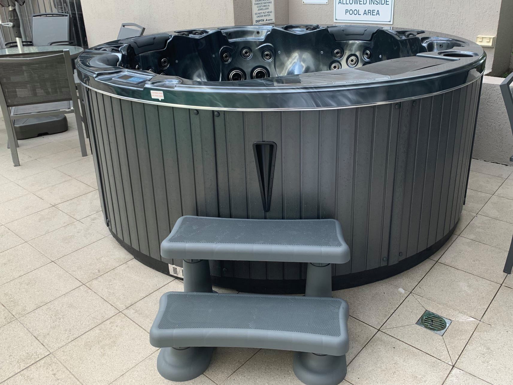 Un jacuzzi con banco integrado y un cartel que indica que es una zona de piscina permitida.