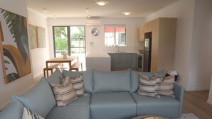 Una sala de estar moderna con un sofá modular, una mesa de comedor y una zona de cocina.