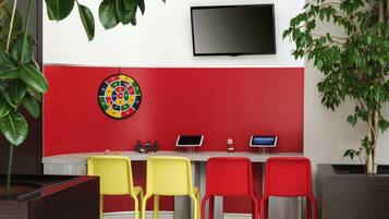 A room with a dartboard, two tablets, and three chairs.