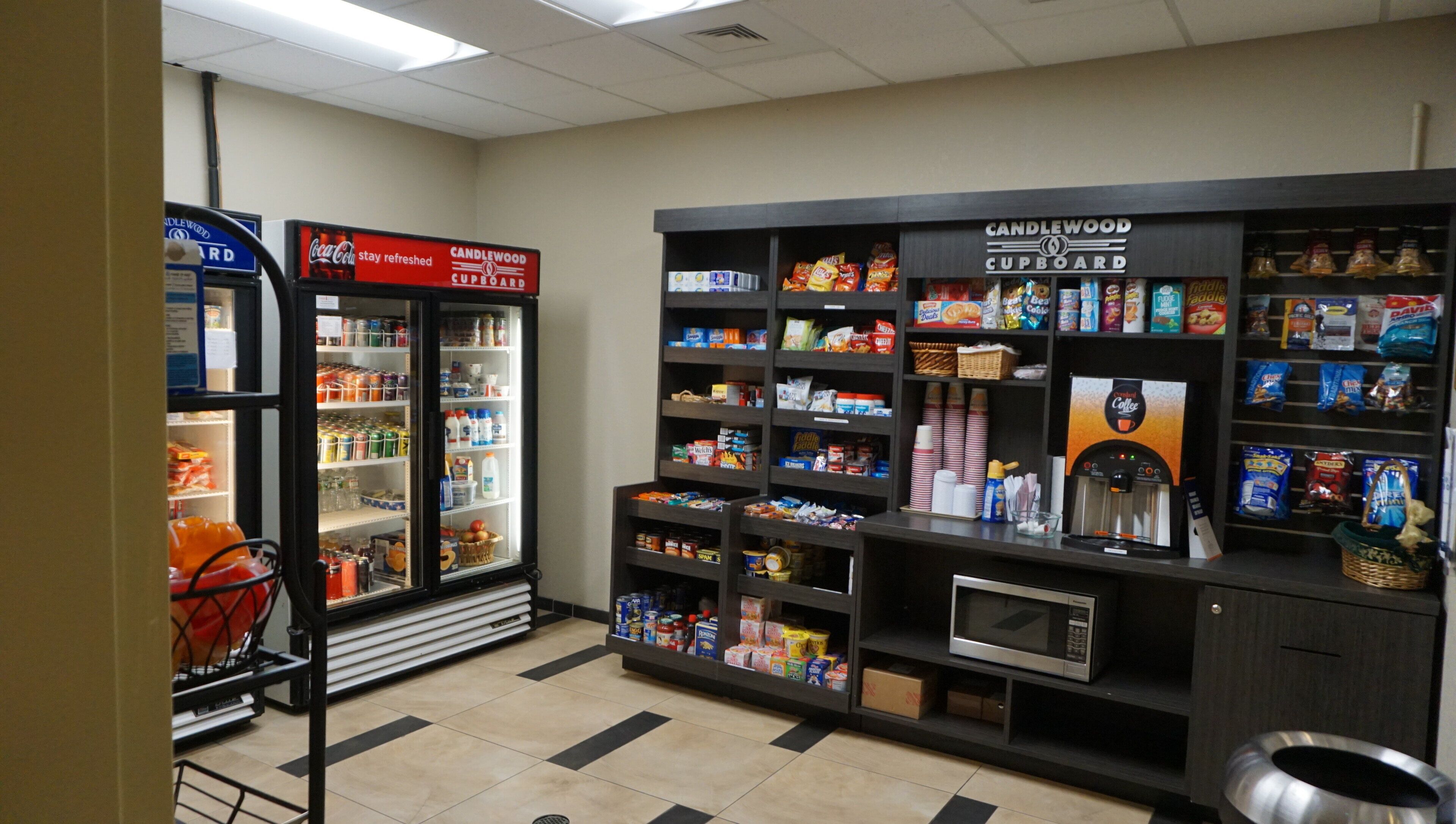 A self-service beverage station with a refrigerator, microwave, and coffee machine.