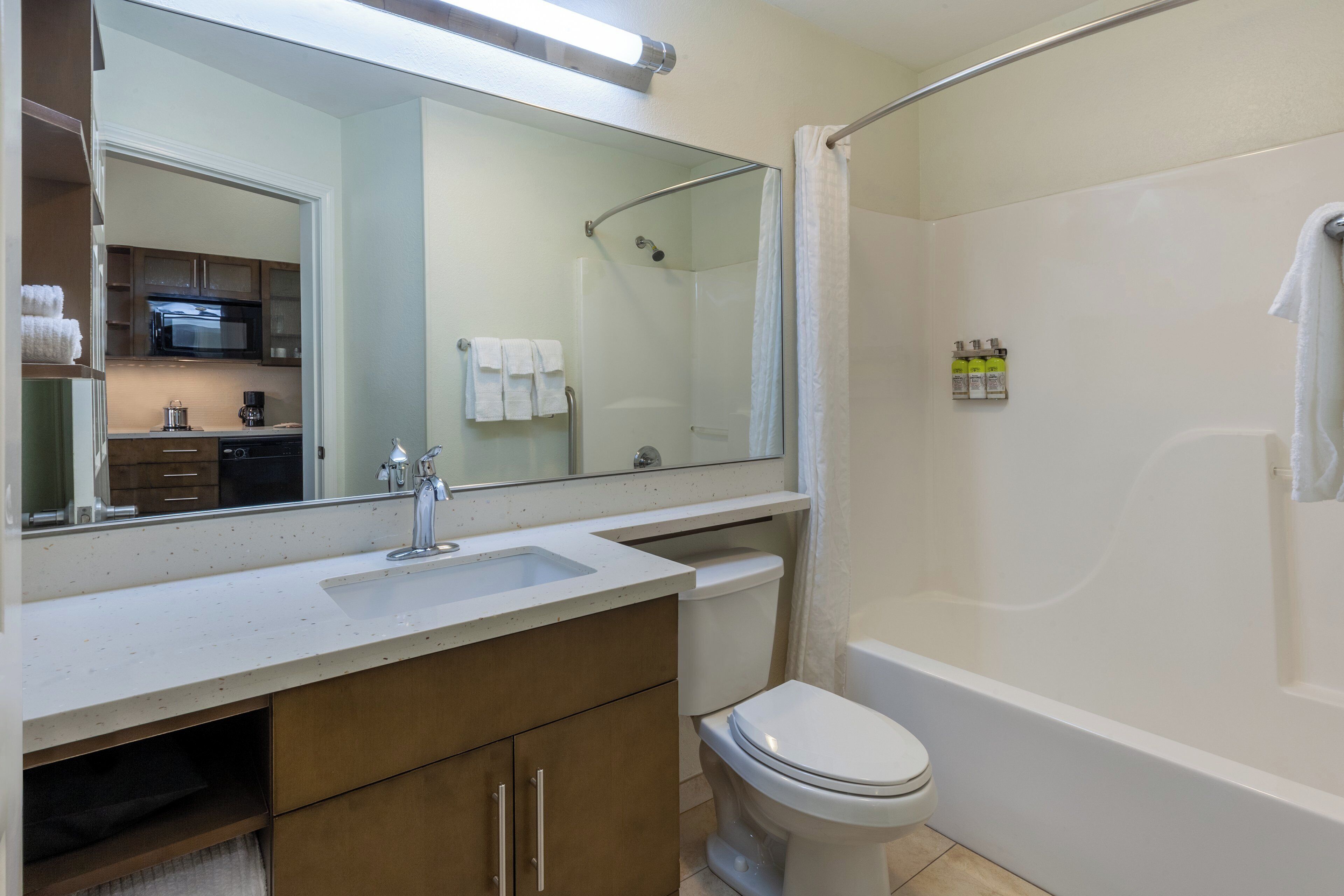 Un baño con lavamanos, inodoro, ducha y espejo.