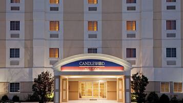 Een hotelentree met een bord waarop 'CANDLEWOOD SUITES' staat en een parkeerplaats ervoor.