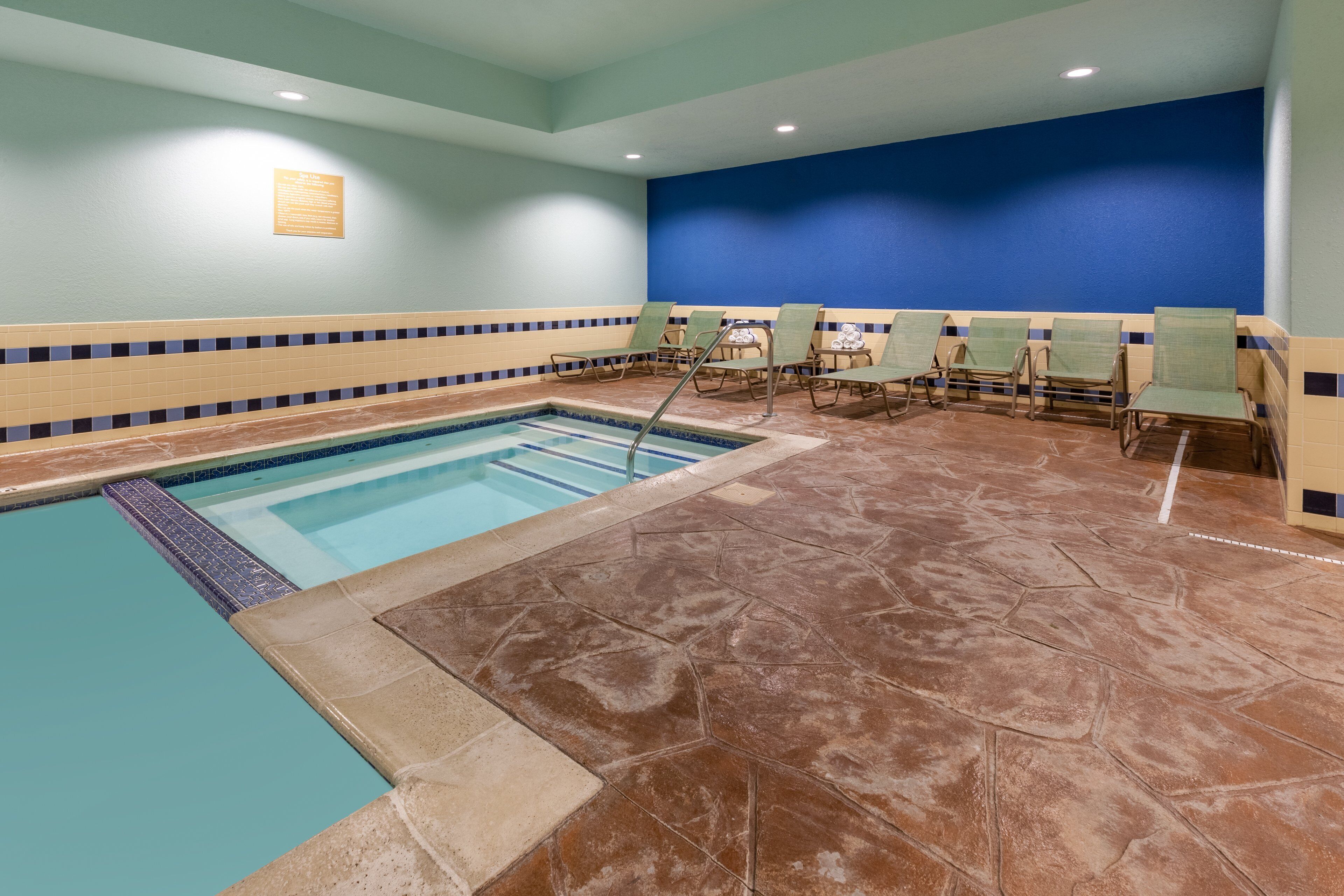 Une piscine avec un bord carrelé et un mur bleu en arrière-plan.