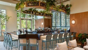 A bar area with multiple seating options, a variety of bottles on the bar counter, and large windows allowing natural light. - JW Marriott Orlando Grande Lakes (Orlando)