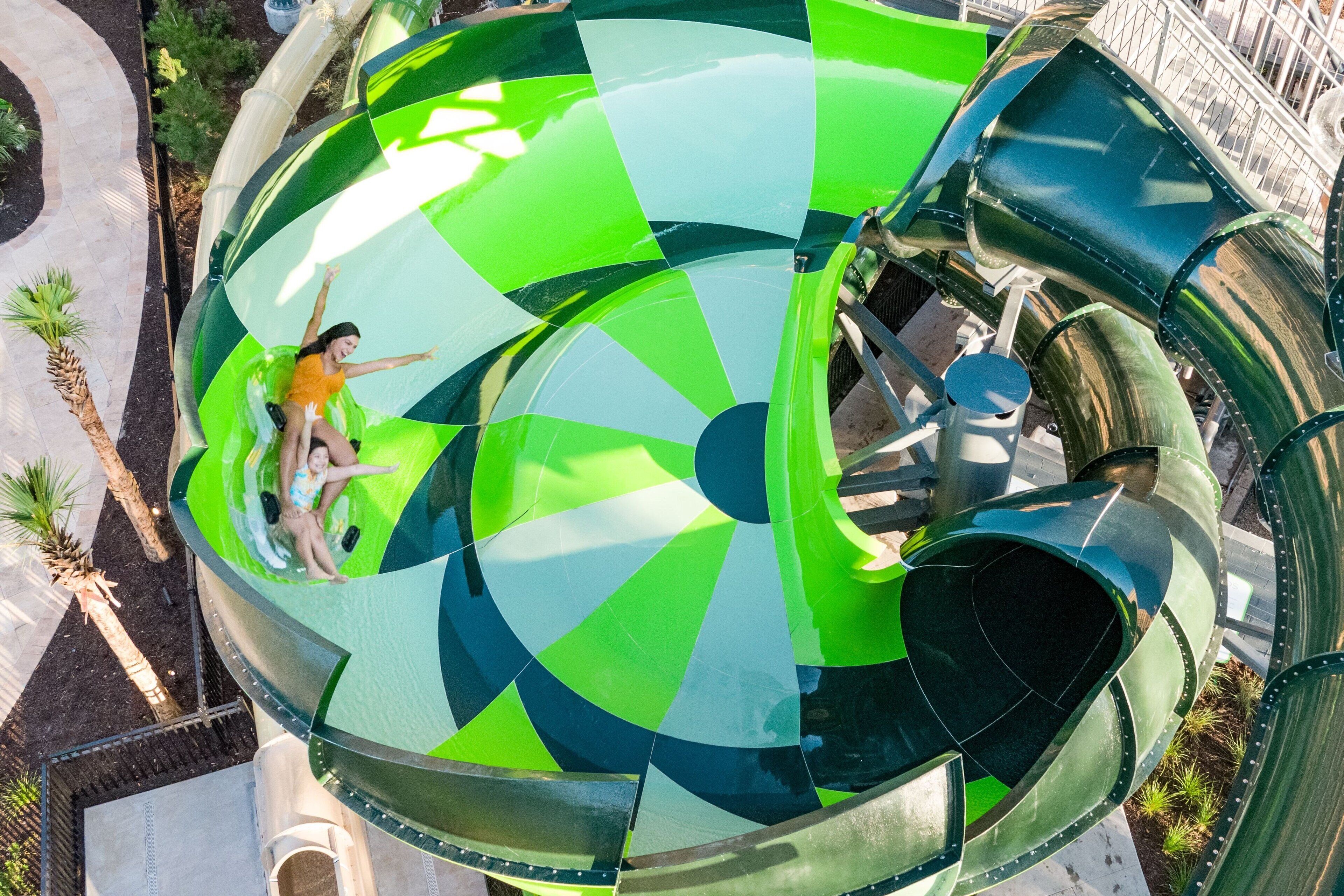 Een grote, groene spiraalwaterglijbaan, met iemand bovenaan.